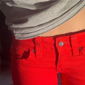 Röda jeans från True Religion - Snygga röda jeans från True Religion med klassisk femficksdesign och broderad bakficka. Perfekta för att sticka ut med. De har en knappgylf och är i en stil som passar till festligare tillfällen. Nästintill oanvända och i nyskick! Skriv gärna vid frågor.