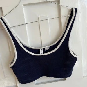 Mörkblå topp med vita kanter - Säljer en mörkblå topp från Divided med vita kanter. Toppen har en enkel och stilren design. Den är i typ handduks material jätte fin till sommaren! 🤍