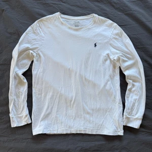 Vit långärmad tröja från Ralph Lauren - Säljer en stilren vit långärmad tröja från Ralph Lauren. Tröjan har en broderad logga på bröstet och är i en bekväm slim fit. 