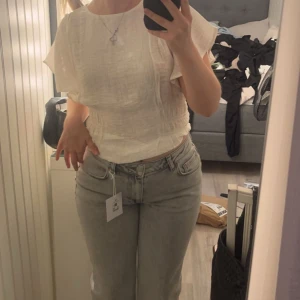 Vit blus med volangärmar - Säljer en söt vit blus med volangärmar och rund hals. Blusen har en luftig passform och är perfekt för varmare dagar. Den är tillverkad i ett lätt och bekvämt material.