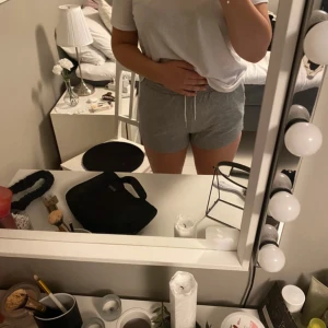 Grå mjukisshorts med snörning - Säljer ett par bekväma grå mjukisshorts med elastisk midja och snörning. Perfekta för en avslappnad dag hemma eller lätt träning. De har en lös passform och är gjorda i mjukt material.