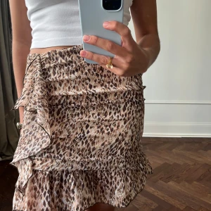 Leopardmönstrad kjol med volang - Trendig kortkjol med leopardmönster och volangdetaljer. Perfekt för en stilfull look.