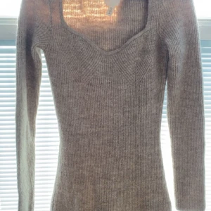 Grå stickad klänning  - Säljer en stilren grå stickad klänning med  v-ringning. Tröjan har långa ärmar och en ribbad struktur som ger en snygg passform. Perfekt för kyligare dagar! Den är från HM i storlek S 