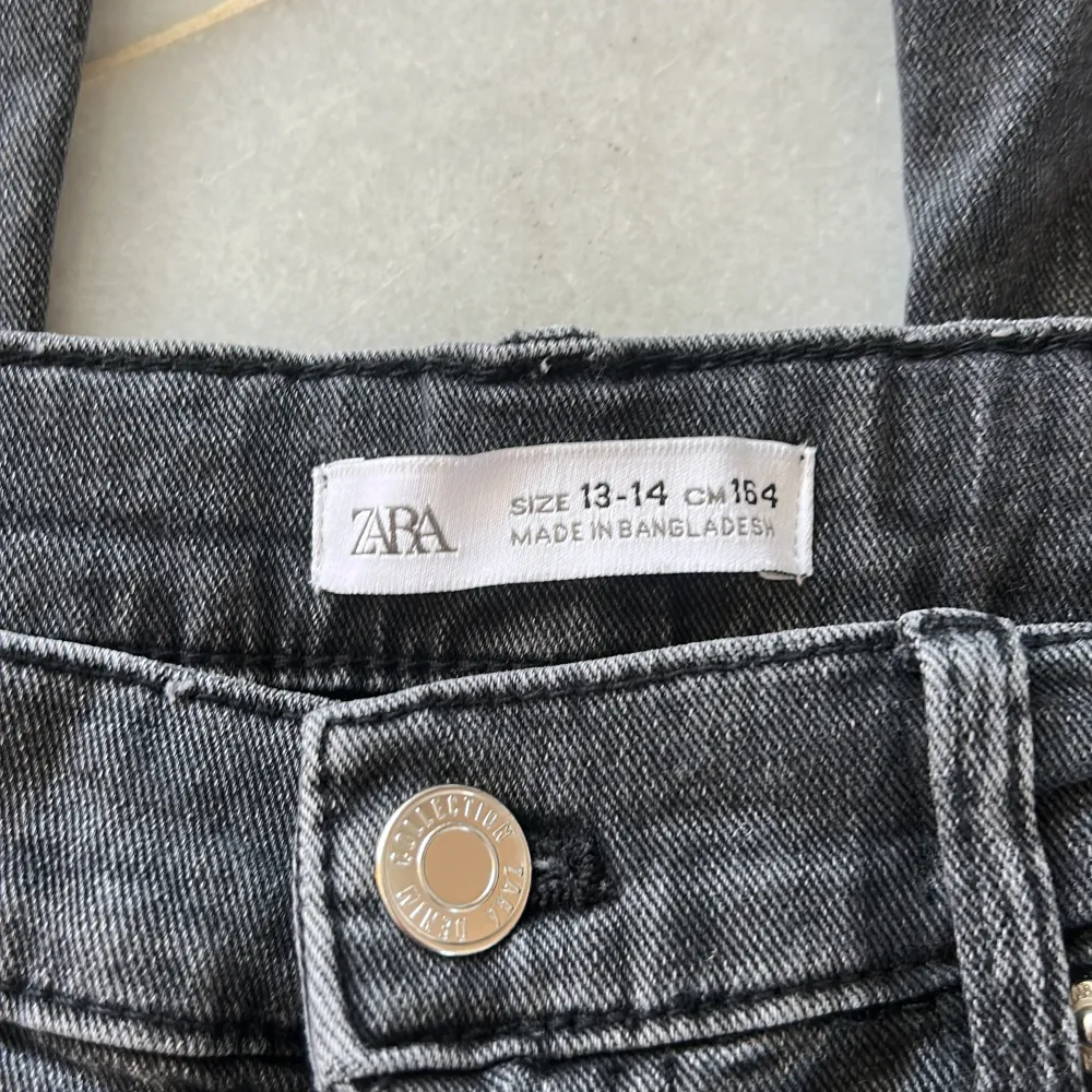 Snygga svarta lågmidjade bootcut jeans från Zara i storlek 164 med slits. . Farkut & Housut.