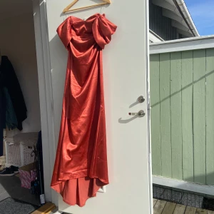 Röd koral axelbandslös långklänning - Säljer en elegant röd axelbandslös långklänning i ett glansigt material. Passar 36-38 och kanske 40 stretch.festklänning koral.Perfekt för speciella tillfällen med sin dramatiska och stilrena design. Klänningen har en vacker drapering och en smickrande passform.Flytt rea: Massor av tjej/damkläder (XS–XL),  30 st festklänningar storlek 32-42, 3 brudklänningar  skor 38,39,40,41 jackor dekoration byrå & mycket mer!  Pris diskuteras., Kan skicka fler bilder   skicka PM vid intresse!