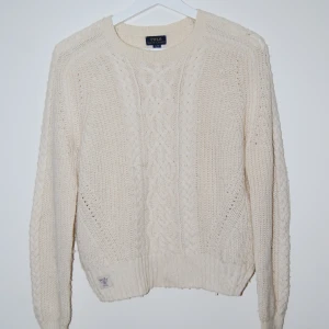 Vit stickad tröja från Polo Ralph Lauren - Säljer en stilren vit stickad tröja från Polo Ralph Lauren. Tröjan har ett klassiskt flätmönster och långa ärmar. Perfekt för kyliga dagar med sin mjuka och varma känsla. Ett måste i garderoben för den som älskar tidlös design. Den är i bra skick och gjord i ett väldigt mjukt och bekvämt material. Den är i storlek XL