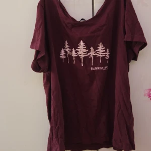 Vinröd t-shirt med tryck - Säljer en vinröd t-shirt med ett tryck av träd och texten 'Outdoor Life' på framsidan. T-shirten har korta ärmar och en avslappnad passform. Perfekt för en casual look!