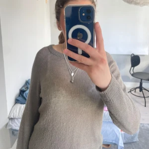 Grå brun stickad tröja - Säljer en mysig beige stickad tröja med rund halsringning. Tröjan är glest stickad och lite genomskinlig samt lite nopprig