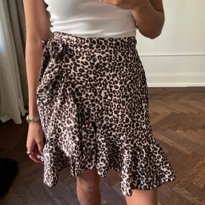 Leopardmönstrad kjol från Chelsea Girls - Snygg leopardmönstrad kjol från Chelsea Girls med volangdetaljer och omlott-design. Kjolen har en knytning i midjan och är perfekt för att ge en trendig touch till din outfit.