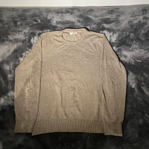 Beige tröja från Lindbergh - Säljer en stilren beige tröja från Lindbergh i slim fit. Tröjan har långa ärmar och ribbade muddar vid ärmslut och nederkant. Perfekt för en elegant och avslappnad look.