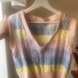 Randig stickad väst - Säljer en färgglad stickad väst i storlek S. Men passar även M skulle jag säga. Västen har breda ränder i pastellfärger som rosa, blå, gul och lila. Den är v-ringad och har en ribbad kant vid ärmhålen och nederkanten. Perfekt för att liva upp garderoben!
