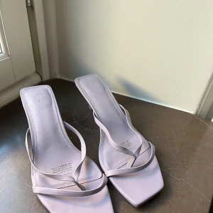 Ljuslila sandaler från H&M - Snygga ljuslila sandaler från H&M med en fyrkantig tå och tunna remmar. Perfekta för varma dagar och ger en stilren look. Sandalerna har en enkel design som passar till många olika outfits.