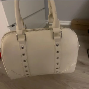 Väska  - Säljer denna vita väska med silver detaljer, köpt här på plick men har inte kommit till användning för mig. Vet dock inte hur andvänd den är utan förra ägaren men inga defekter vad jag sett 💕