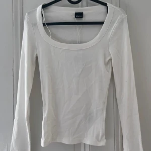 Vit långärmad topp från Gina Tricot - Säljer en stilren vit långärmad topp från Gina Tricot. Toppen har en rundad halsringning och är tillverkad i ett mjukt material som ger en bekväm passform. Perfekt för lager-på-lager eller som den är.