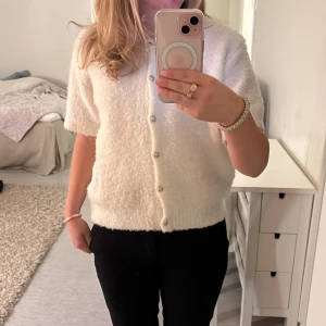 Vit kortärmad kofta med knappar - Säljer en söt vit kofta med korta ärmar och knappar framtill. Bara använd en gång och säljer då den inte används längre. Är i storlek L men passar mig som har S, från Gina Tricot☺️