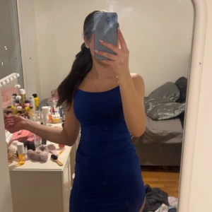 Blå tight klänning - Snygg blå klänning med tight passform och smala axelband. Perfekt för en kväll ute. Klänningen har en stilren design som framhäver figuren.