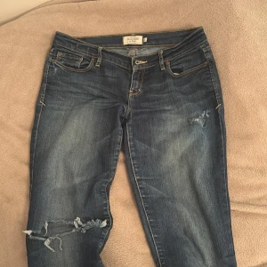 Blå bootcut lowwaist jeans med slitningar - Midejmått rakt över är 38,5cm och de passar bra på mig som är 170 men skulle även kunma passa en 168 också💕 De är köpa på plick och den ända defekten skulle jag säga är sista bilden men det är inget man tänker på när man har på sig de❤️