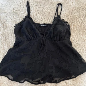 Svart linne från Gina Tricot - Säljer ett svart linne från Gina Tricot med justerbara axelband och volangdetaljer. Kontakta för fler frågor m.m. Köparen står för frakten 💗💗💗