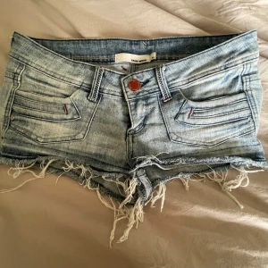 Blå jeansshorts med  - Snygga blå jeansshorts från med fransiga kanter och låg midja. Midjemått 39