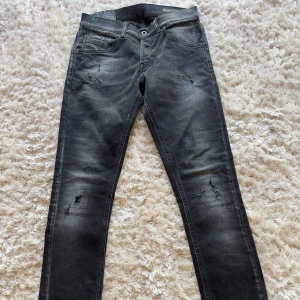 Dondup Ritche svart/grå i nyskick w29 - Snygga svart/grå jeans från Dondup med slitningar. Jeansen har en tightare passform som sitter snyggt längs hela benet. Perfekta för dig som gillar en modern och edgy stil. Knappt använda och i mycket bra skick.