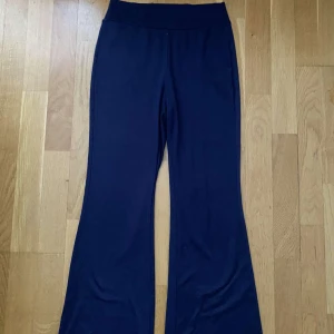 Marinblåa utsvängda byxor - Marinblåa byxor med bootcut/utsvängda passform och lågmidja. Byxorna är i ett mjukt och stretchigt material, Inga fickor eller dragkedjor, Använd fåtal gånger, lätt material passar för sommar/våren. 