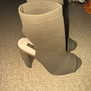 Beige stickade stövletter med klack - Snygga beige stövletter från Primark i stickat material. Skorna har öppen tå, hög blockklack och en tight passform som sitter som en strumpa runt foten. Perfekta för dig som vill ha en trendig och edgy look.