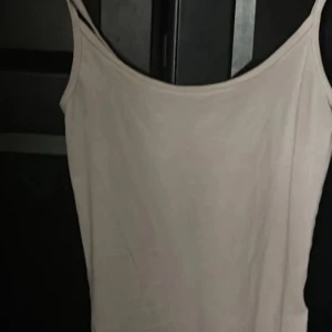 Beige linnetopp med smala axelband - Enkel och stilren beige linnetopp med smala axelband. Perfekt att matcha med jeans eller kjol för en clean look. Tunt och mjukt material som känns skönt mot huden.