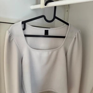  Croppad topp  - Superfin vit croppad topp från Shein med fyrkantig ringning och långa ärmar. Toppens material är mjukt och stretchigt, perfekt för en clean och stilren look. Passar snyggt till både jeans och kjol för en trendig vibe.