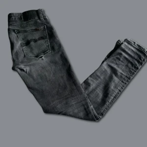 Nudie Jeans - Svarta Nudie jeans som är Slim Fit och ”Hyperflex”. Skick 7/10. Storlek 31/32. Finns en slitning på högra bakfickan, påverkar ej fickans funktion och personligen tycker jag det är rätt snyggt. Hör av er vid minsta fundering!