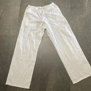 Vita linnebyxor med snörning - Snygga och luftiga vita linnebyxor med rak passform och elastisk midja med snörning. Perfekta för varma dagar och chill vibes. Byxorna har fickor i sidorna och är tillverkade i ett tunt och skönt linnematerial.