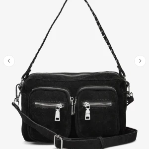 Svart mocka axelväska från Noella - Snygg svart axelväska i mocka från Noella med två framfickor och silvriga dragkedjor. Väskan har både kort och lång rem, så du kan bära den på olika sätt. Perfekt storlek för det mesta då det är en lite större modell. Älskar den och får plats med allt men kommer tyvärr inte till användning längre