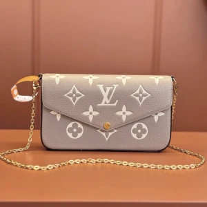 Louis Vuitton grå axelväska med kedja - Grå axelväska från Louis Vuitton med ikoniskt monogrammönster i vitt. Väskan har guldfärgad kedjerem, kuvertformad front med tryckknapp och medföljande plånbok och korthållare. Tillverkad i präglat skinn för en lyxig känsla och stilren look.