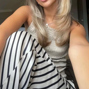 Randiga sidenbyxor  i vitt och svart - Snygga sidenbyxor från HM med svartvita ränder. Byxorna har en luftig och flowy passform som känns både trendig och bekväm. Perfekt för dig som gillar en stilren men ändå iögonfallande look.