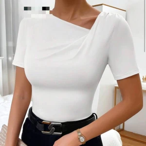 Vit oneshoulder topp - Säljer en stilren vit topp med oneshoulder-design och kort ärm. Toppen har en lätt drapering vid axeln och sitter tight mot kroppen. Perfekt för dig som gillar minimalistisk och modern stil. Aldrig använd.