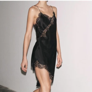 Svart satinklänning med spetsdetaljer - Supersnygg svart kortklänning i satin med spets detaljer. Ny med prislappen på 