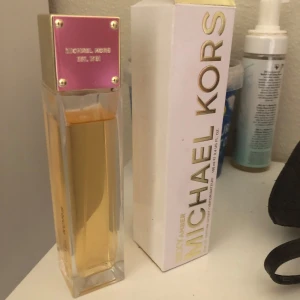Michael Kors Sexy Amber parfym 100ml - Lyxig parfym från Michael Kors i doften Sexy Amber. Flaskan är rektangulär i genomskinligt glas med guldig vätska och ett fyrkantigt lock i guld och rosa metallic. Kommer med originalkartong i vitt och guld. Perfekt för dig som gillar eleganta och moderna dofter.