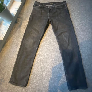 Svarta jeans från Jack & Jones Tapered - Säljer ett par svarta jeans med lite ljusning vid knäna från Jack & Jones, modell Tapered Mike. Storlek 32/30. Dom är knappt använd. Ny pris 599