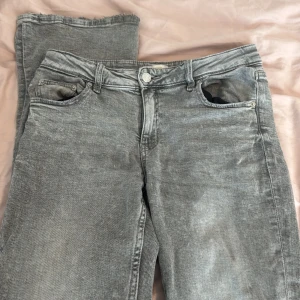 Grå bootcut jeans från Gina Tricot - Snygga grå jeans från Gina Tricot i bootcut-modell. Jeansen har klassisk femficksdesign, knapp och dragkedja framtill samt utsvängda ben. Perfekta för dig som gillar en retroinspirerad look.