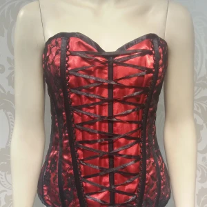 Korsett med snörning i ryggen (ej underklädeskorsett) XL - Vacker korsett med snörning i ryggen ( Ej underklädeskorsett). Helt ny. Snygg stt ha en skjorta under eller en kava över.