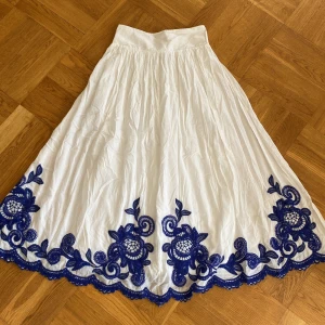 LÅNGKJOL från Zara - En så fin vit långkjol från Zara med broderade blåa detaljer längst ner som endast är använd en gång!❤️😍🥰 Den är i storlek s med en midjelängd på 36 centimeter och en längd på 91 centimeter men den är väldigt stretchig❤️☺️ Säljer för att den tyvärr inte kommer till användning!💕