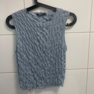 Ljusblå ärmlös topp från Gina Tricot - Säljer en ljusblå topp från Gina Tricot med ett strukturerat mönster. Enkel att matcha med både jeans och kjol. Endast provad!