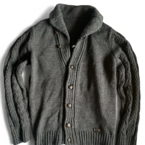 Mörkgrå stickad kofta från Dolce & Gabbana - Säljer en mörkgrå stickad kofta från Dolce & Gabbana med snygga knappar framtill och grovstickade detaljer längs ärmarna. Den är gjord i extremt bra material. Koftan har en bred krage och ribbade muddar vid ärmslut och nederkant. Perfekt för sommarnätter nu när det är kommandes 🤞 skriv för mer frågor osv, säljer då jag gått ner i vikt på sistone och storleken är lite för stor.