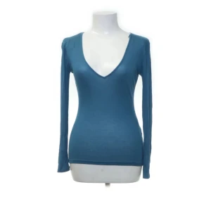 Blå ribbad långärmad topp från Zara - Säljer en blå långärmad topp från Zara med djup v-ringning. Tröjan är ribbad och har en tight passform som framhäver figuren. Perfekt att styla med en jeanskjol för en y2k dripp💕