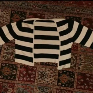 Randig kofta från Hunky Dory - Säljer en svartvit randig kofta från Hunky Dory i storlek L. Koftan är öppen framtill och har långa ärmar. Materialet känns mjukt och stickat, perfekt för lager-på-lager-stil.