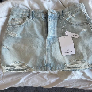 Ljusblå jeanskjol från Pull&Bear - Säljer en ljusblå jeanskjol från Pull&Bear med slitna detaljer och råa kanter. Storlek m men liten i storlek. Helt oanvänd med prislappar kvar. Skriv vid intresse 