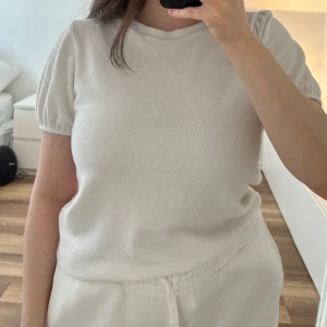 Vit kortärmad topp med puffärm - Säljer en söt vit topp med korta puffärmar och rund halsringning. Materialet är mjukt och lite strukturerat, vilket ger en mysig känsla. Storlek L men liten i storleken. Passar mig som annars har storlek S. 