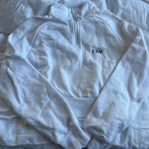 Vit halvzip hoodie från ICIW - Säljer en vit hoodie från ICIW med halv dragkedja och broderad logga på bröstet. Tröjan har långa ärmar, ribbade muddar och hög krage. 