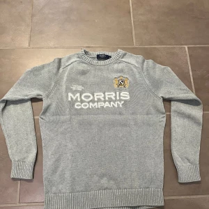 Ljusgrå stickad tröja från Morris - Snygg ljusgrå stickad tröja från Morris med broderad logga och text framtill.