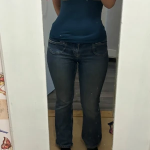 Blå bootcut jeans från H&M - Säljer ett par klassiska blå bootcut jeans från H&M. Jeansen har normal passform, fem fickor och stängs med knapp och dragkedja. Perfekta till vardags och lätta att matcha med olika toppar.