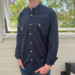 Mörkblå Ralph lauren skjorta - Säljer min mörkblåa Ralph Lauren skjorta, jätte fint skick, modellen är slim fit och sitter väldigt bra på kroppen, postas inom 48h 